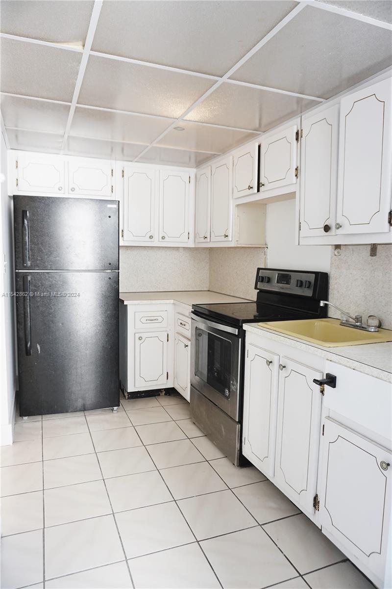 1340 Lincoln Road, Unit 608 Miami Beach, FL 33139 - Photo 5 of 10 a kitchen with white cabinets a refrigerator and a stove top oven