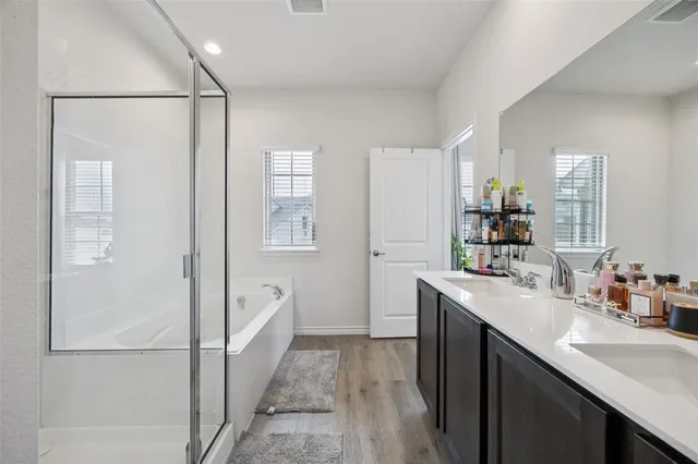 a spacious bathroom with a double vanity sink a mirror and shower