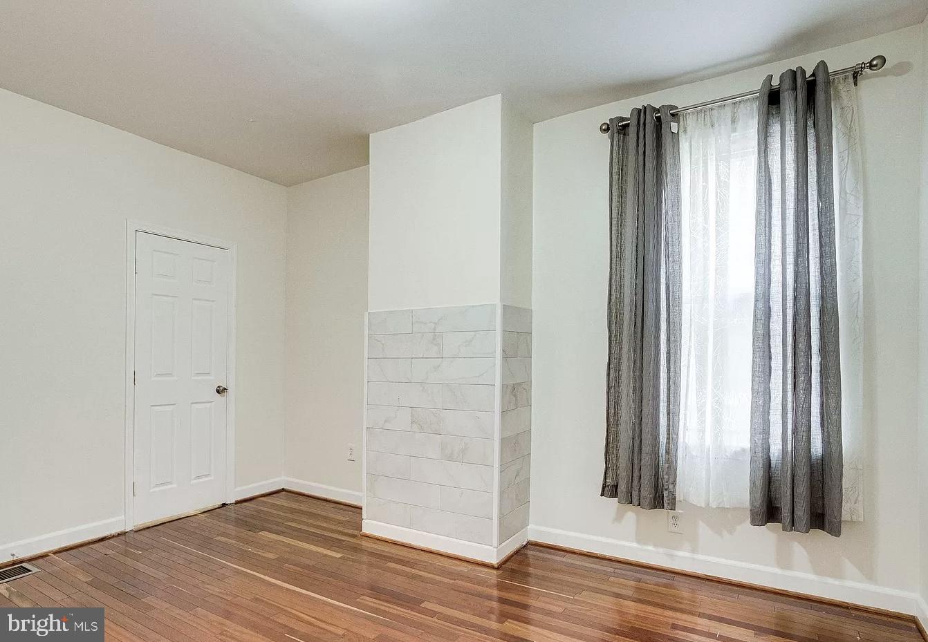 595 Columbia Road Northwest Washington, DC 20001 - Photo 20 of 36 an empty room with wooden floor and a window