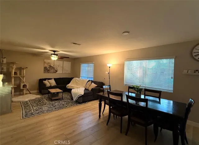 a living room with couches chairs and kitchen view with wooden floor