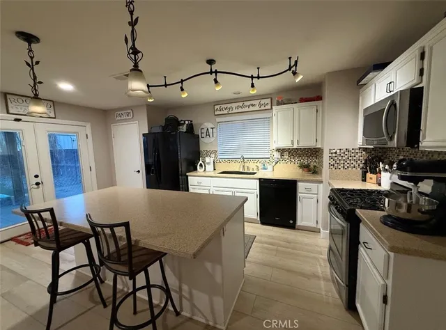 a kitchen with stainless steel appliances granite countertop a stove a sink a microwave a refrigerator and chairs