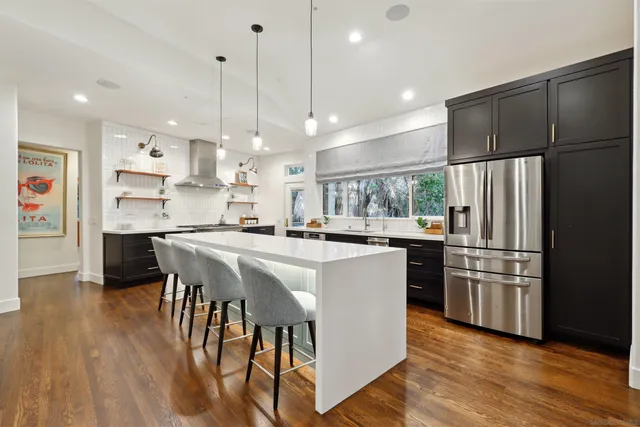 a kitchen with kitchen island a refrigerator a stove a sink and a chairs