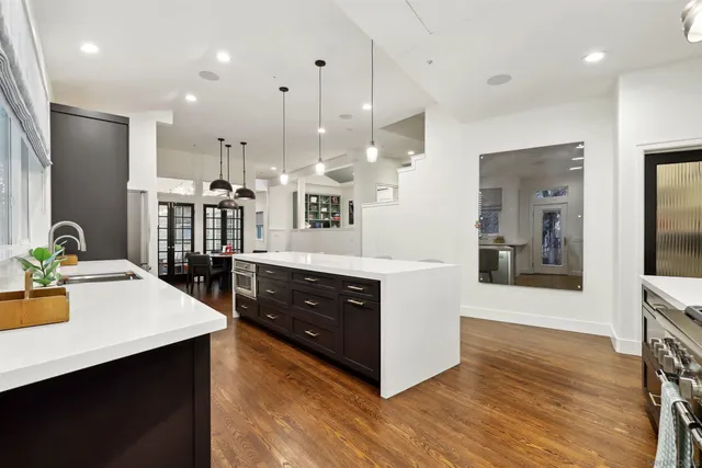 a kitchen with stainless steel appliances kitchen island granite countertop a refrigerator a stove and a wooden floors