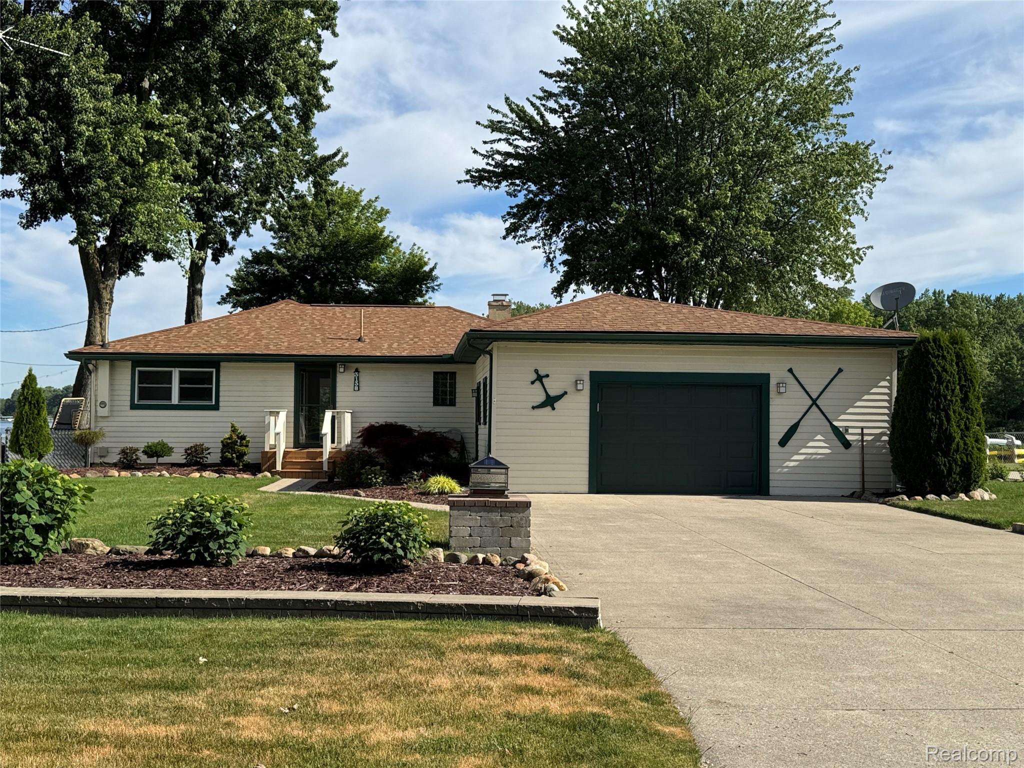 3138 Ponemah Drive Fenton, MI 48430 - Photo 1 of 19 Front exterior featuring light-colored siding with dark green trim, a concrete driveway, and an attached two-car garage