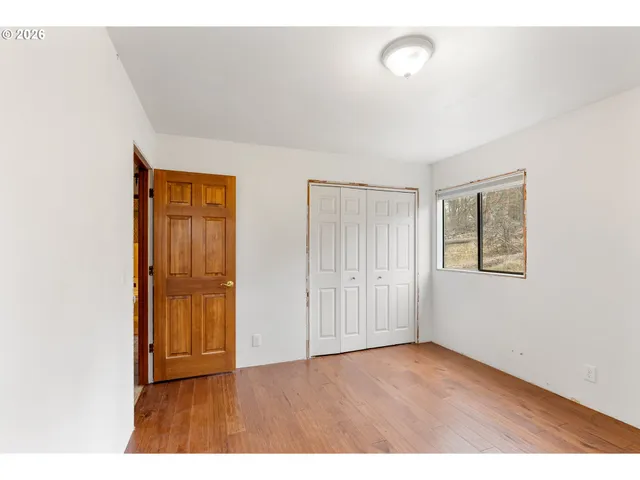a view of an empty room with closet and a window
