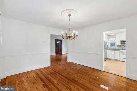 a view of a room with wooden floor chandelier and a kitchen