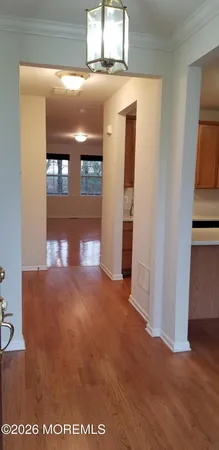 a view of a hallway with wooden floor and a living room