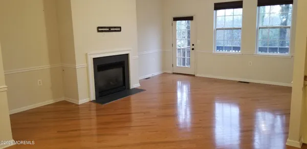 a view of an empty room with glass door and wooden floor