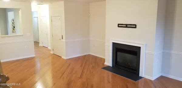 a view of an empty room with wooden floor and a fireplace