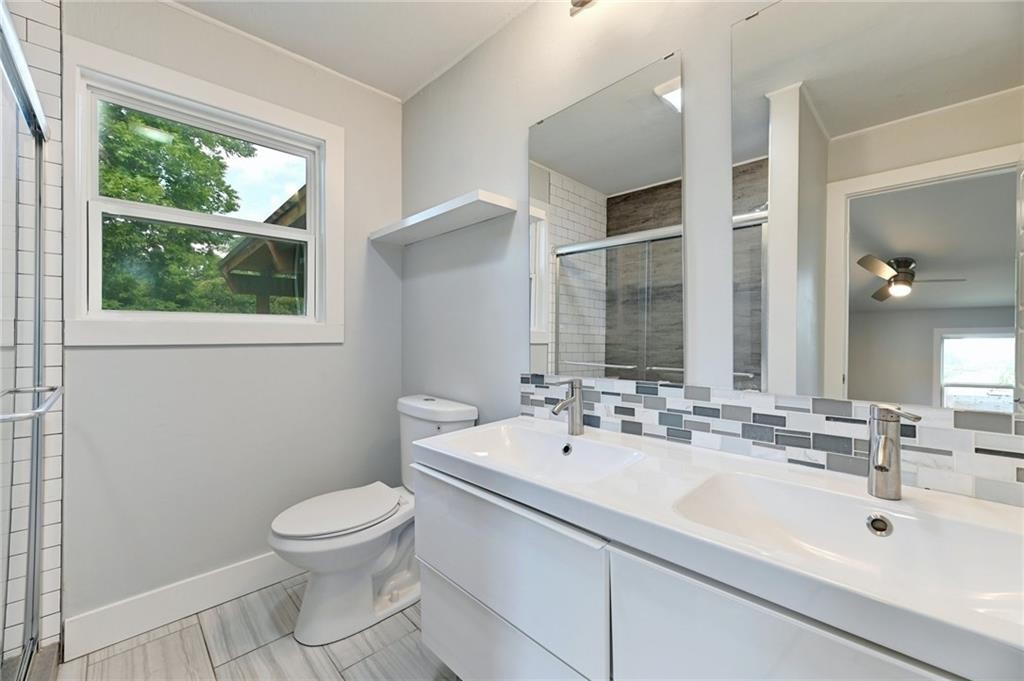 8318 Burrell Drive Austin, TX 78757 - Photo 15 of 27 Bathroom featuring decorative backsplash, double vanity, a stall shower, a ceiling fan, and tile patterned floors