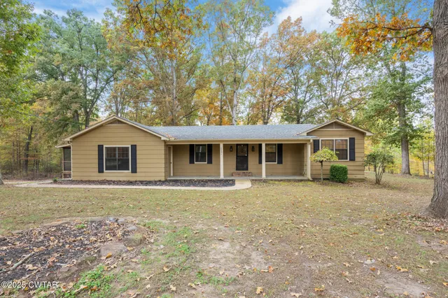 a front view of a house with a garden and trees