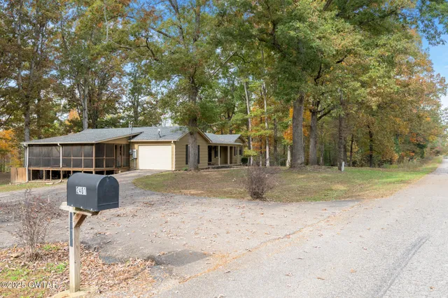 a front view of house with yard space and trees in the background