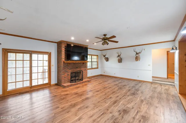 wooden floor in an empty room with a fireplace and a window