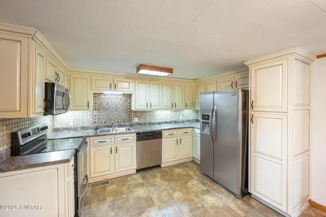 a kitchen with stainless steel appliances granite countertop a refrigerator a stove a sink and a microwave