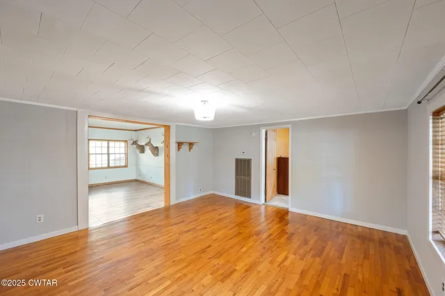 a view of a big room with wooden floor and windows