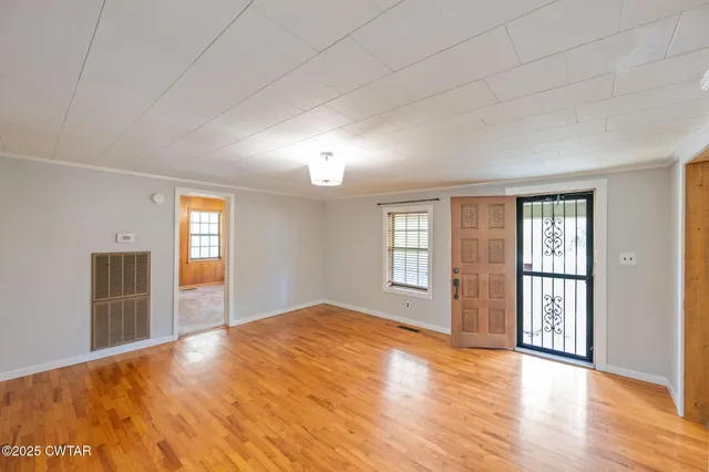 a view of an empty room with window and wooden floor