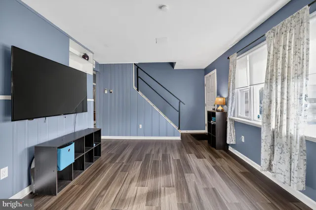 a living room with a flat screen tv on wall and a window