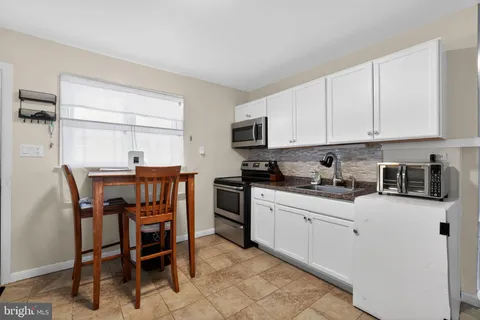 a kitchen with stainless steel appliances kitchen island granite countertop a table chairs sink and cabinets