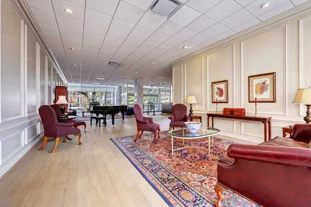 a living room with furniture a rug kitchen view and a large window
