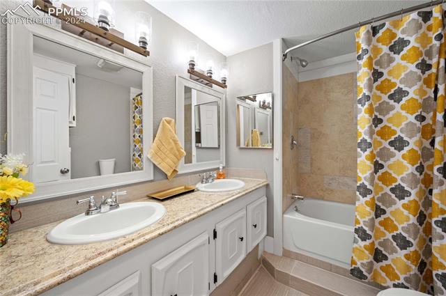 1326 Forest Road Colorado Springs, CO 80906 - Photo 12 of 22 Full bathroom featuring double vanity, shower / tub combo, a textured ceiling, tile floors, and toilet