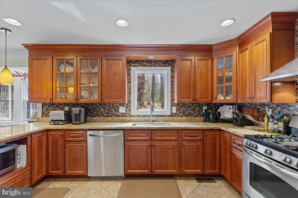 a kitchen with stainless steel appliances granite countertop a stove a sink and a microwave