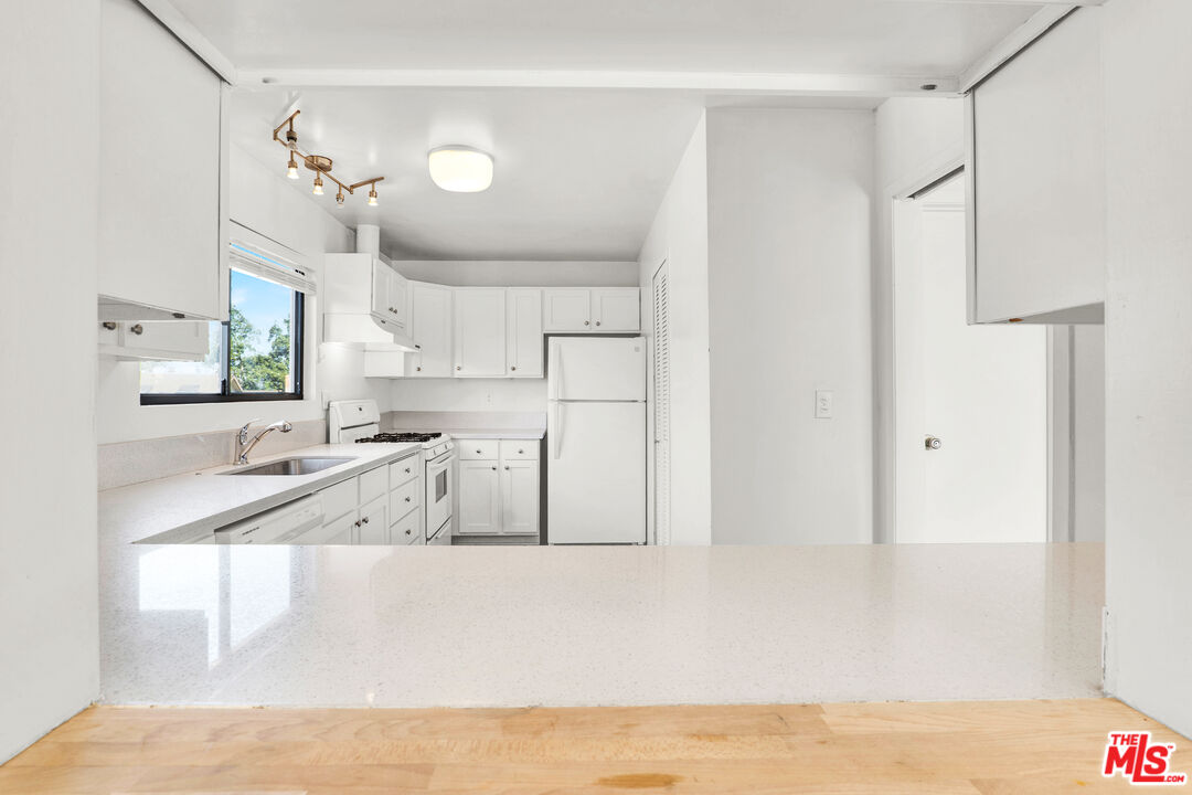 20948 Waveview Drive Topanga, CA 90290 - Photo 5 of 19 a large white kitchen with cabinets and a large window