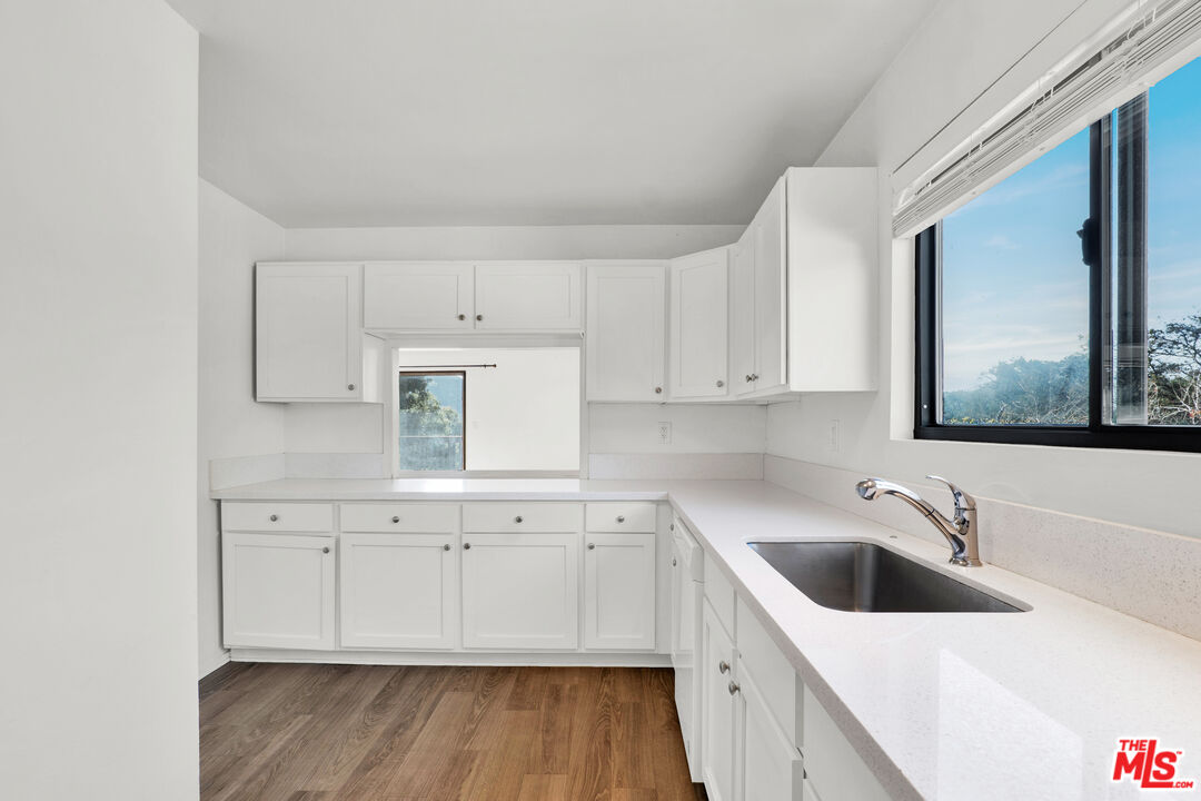 20948 Waveview Drive Topanga, CA 90290 - Photo 6 of 19 a kitchen with a sink dishwasher and white cabinets with wooden floor