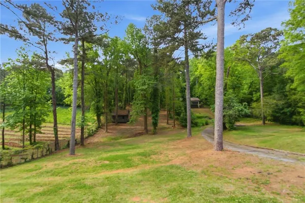 a view of a small house with large tree and wooden fence