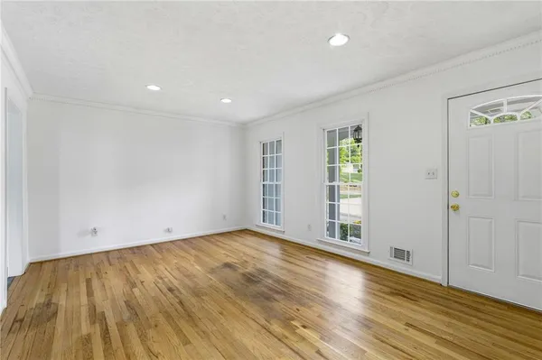 an empty room with wooden floor and windows