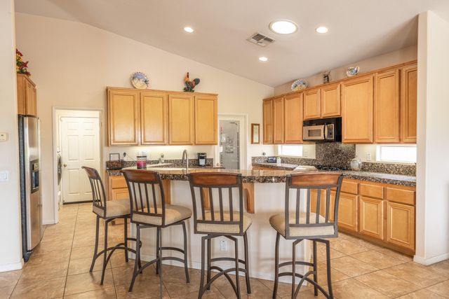 a kitchen with stainless steel appliances granite countertop table chairs sink and cabinets