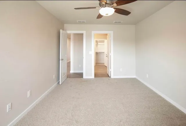 an empty room with a ceiling fan and a window