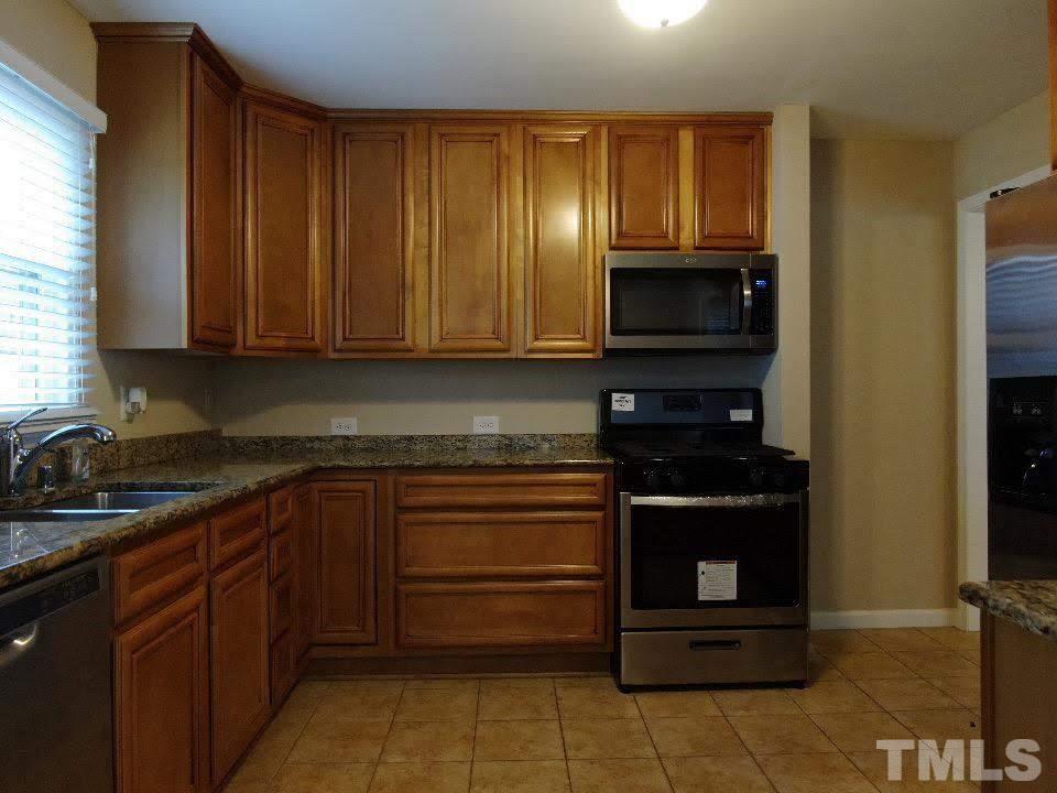 4703 Latimer Road Raleigh, NC 27609 - Photo 14 of 22 a kitchen with stainless steel appliances granite countertop wooden cabinets and a stove top oven
