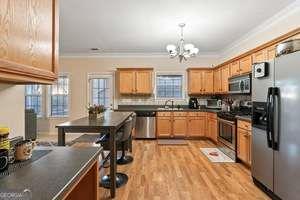 535 Anglewood Trace Stockbridge, GA 30281 - Photo 25 of 73 a kitchen with stainless steel appliances granite countertop a stove top oven a sink dishwasher a dining table and chairs with wooden floor