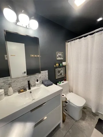 a bathroom with a granite countertop sink a toilet and a mirror