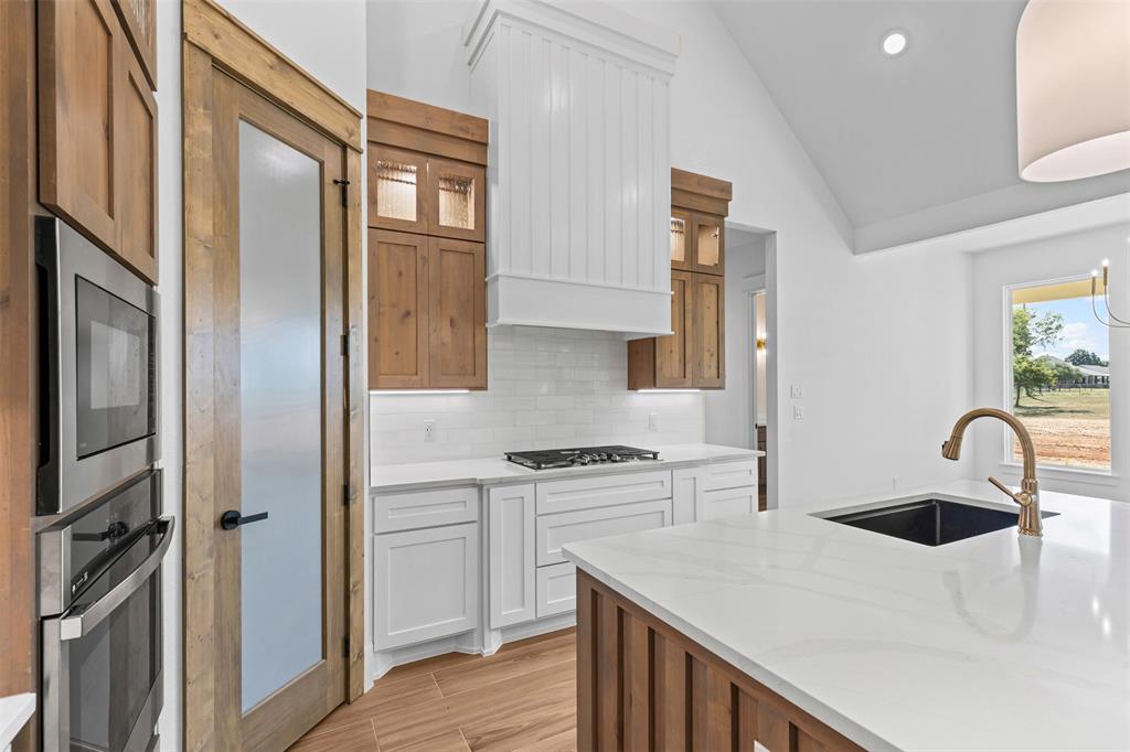 1132 Dobbs Trail Springtown, TX 76082 - Photo 11 of 32 a kitchen with stainless steel appliances granite countertop a refrigerator a sink a stove and white cabinets with wooden floor