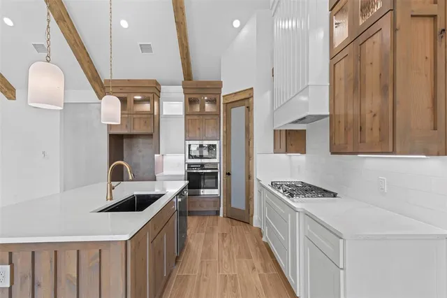 a kitchen with stainless steel appliances a sink a stove top oven a counter space and cabinets