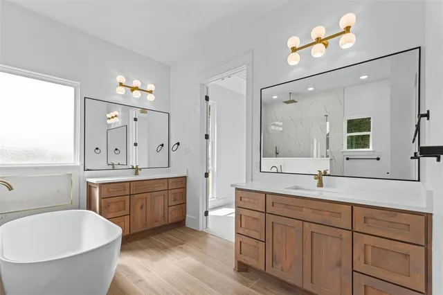 a spacious bathroom with a granite countertop double vanity sink a mirror and a bathtub