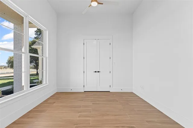a view of an empty room with windows and wooden floor