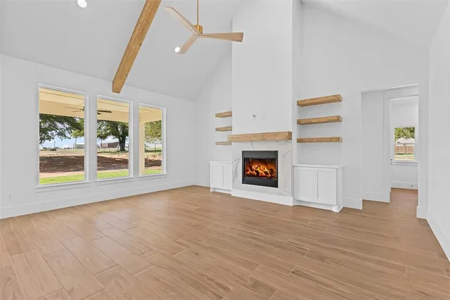 a view of an empty room with wooden floor fireplace and a window