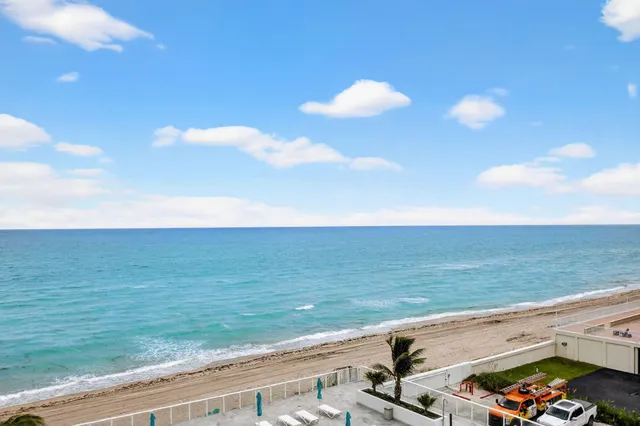 a front view of a multi story residential apartment building with yard and green space