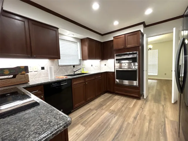 a kitchen with stainless steel appliances kitchen island granite countertop a sink stove and refrigerator