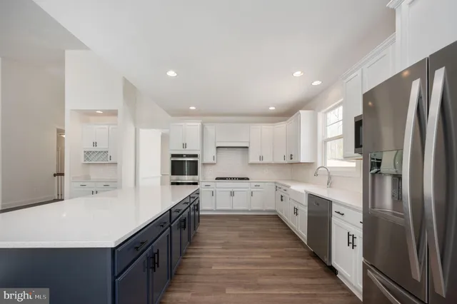 a large kitchen with a large counter top a sink stainless steel appliances and cabinets