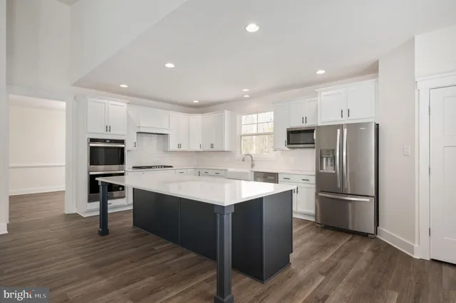 a kitchen with kitchen island stainless steel appliances a sink and a refrigerator