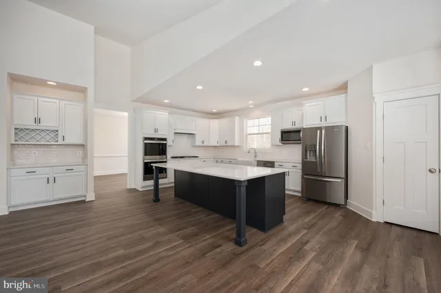 a large kitchen with a center island wooden floor stainless steel appliances and cabinets