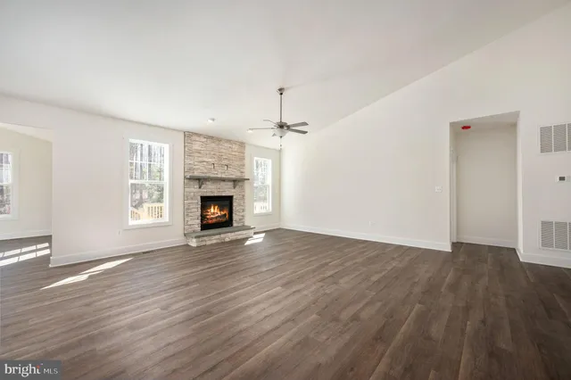 a view of an empty room with wooden floor fireplace and a window