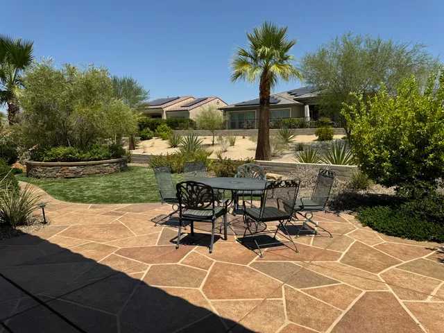 a view of a patio with table and chairs near a barbeque