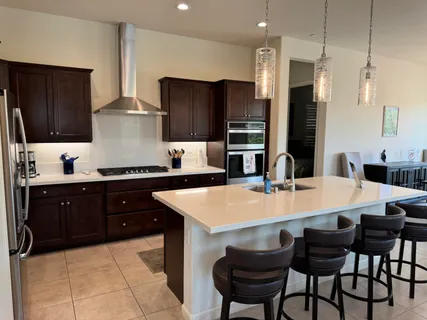 a large kitchen with a table chairs refrigerator and cabinets