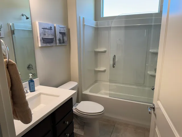 a bathroom with a granite countertop bathtub sink vanity mirror and toilet