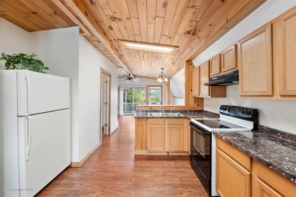 3600 Leghorn Road Grant Valkaria, FL 32950 - Photo 24 of 33 a kitchen with stainless steel appliances granite countertop a refrigerator a sink dishwasher a stove with white cabinets and wooden floor