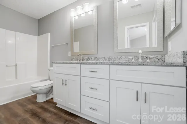 a bathroom with a granite countertop toilet sink and mirror
